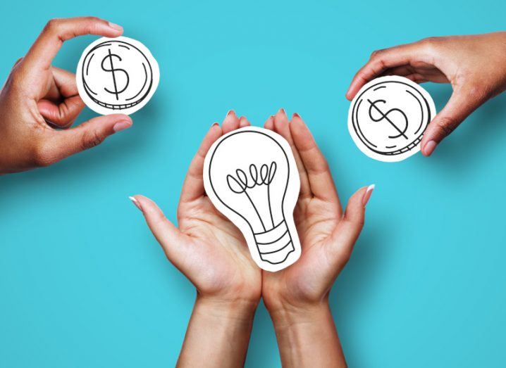 Pair of hands holding a paper drawing of a light bulb with two different hands holding out a paper coin on either side of the image. Turquoise background.