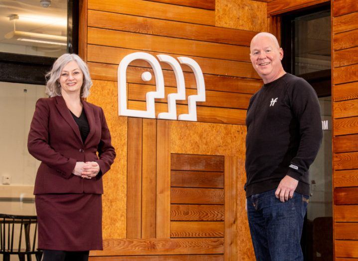 Two people stand beside a wooden wall with the Responsible logo on it.