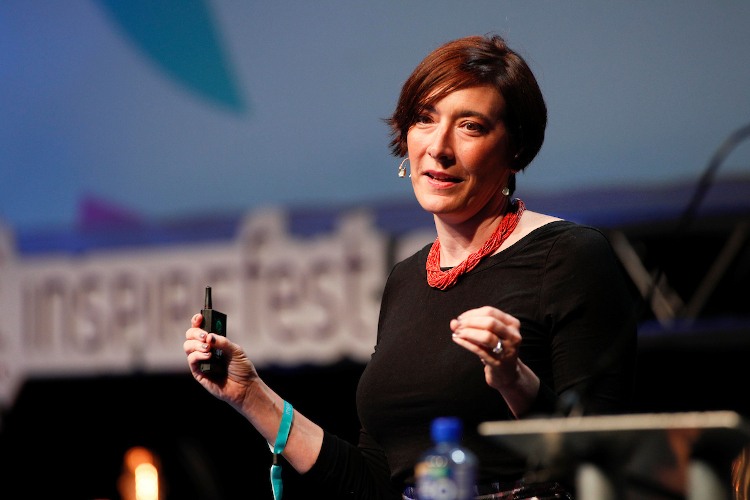 Monica Parker speaking on stage beside a podium at Inspirefest.