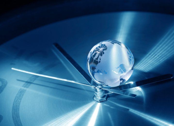 A clock with a glass globe of the earth on top of it, with a slightly blue colouring on the image.