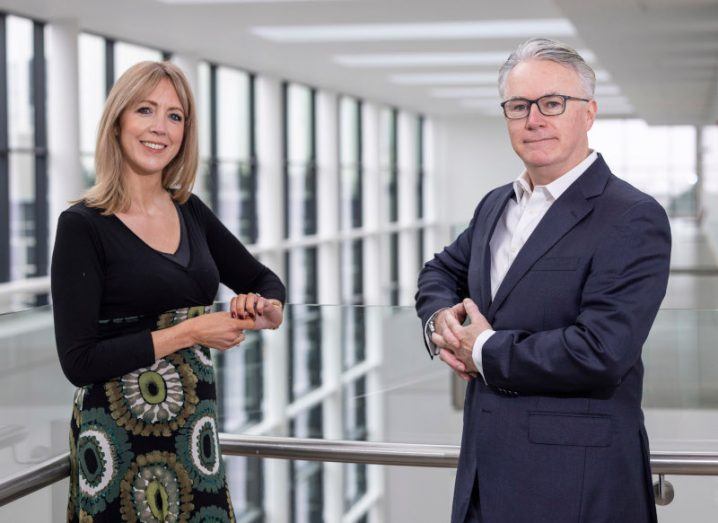 Epicapture founders Dr Antoinette Perry and Edward Simons leaning against a glass railing inside a building.