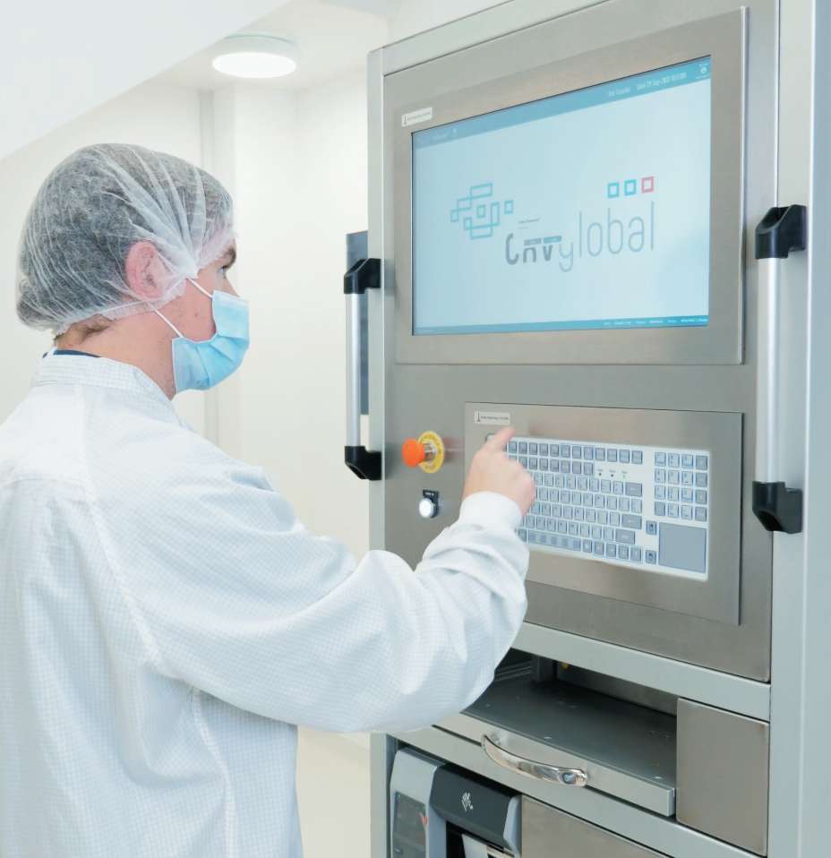 A worker at CXV Global using a machine and dressed in lab gear.