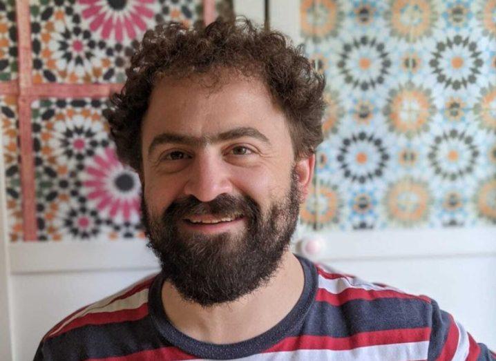 Headshot of a man in a striped shirt with a colourful wall behind him. He is Prof Mark Mitchison of Trinity College Dublin.