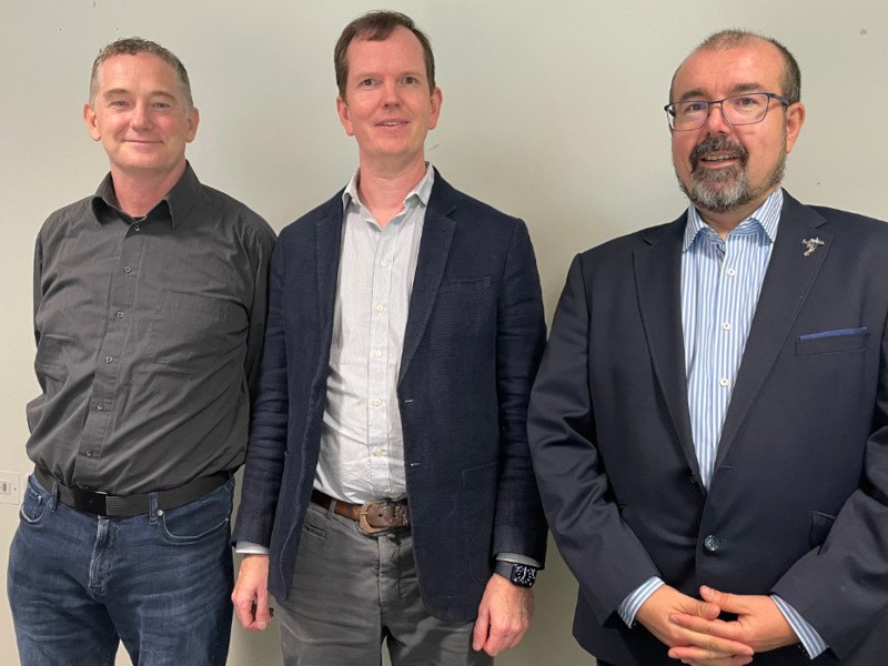 Three men stand for a photo.