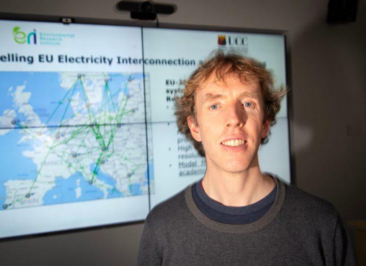 A man standing in front of an energy modelling presentation on a screen.