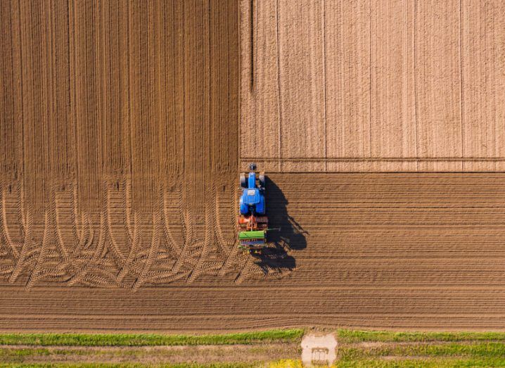 Aerial view of a blue tractor plowing a field.