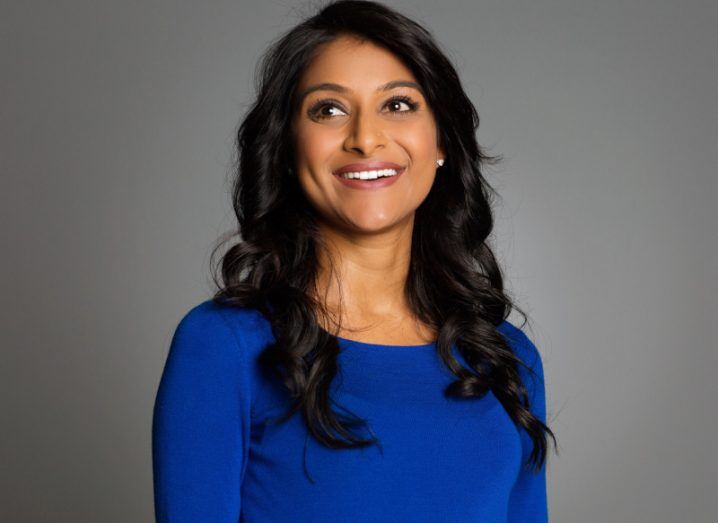 A woman wearing a blue jumper smiles and looks off-camera. She is Rinki Sethi, VP and CISO of Bill.