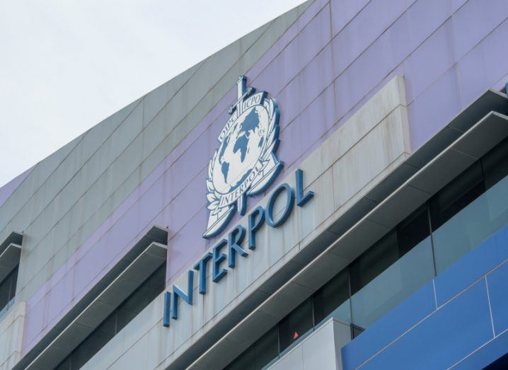 The Interpol logo on the side of a building, with a grey cloudy sky visible above.