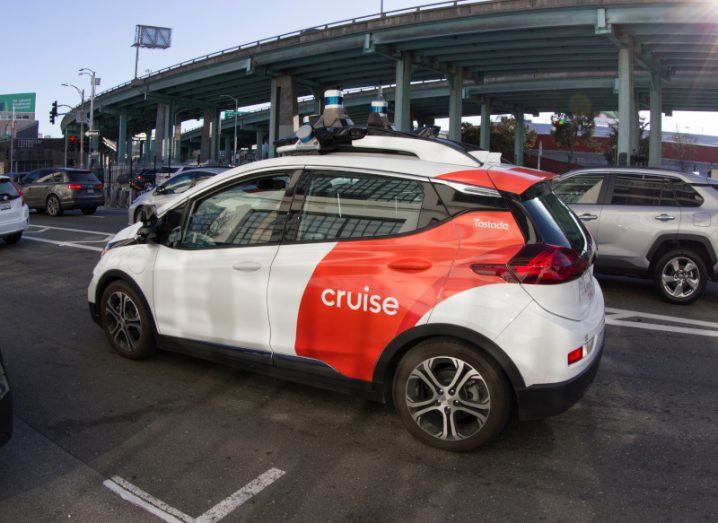 A taxi in the middle of a road with the Cruise logo on the side.