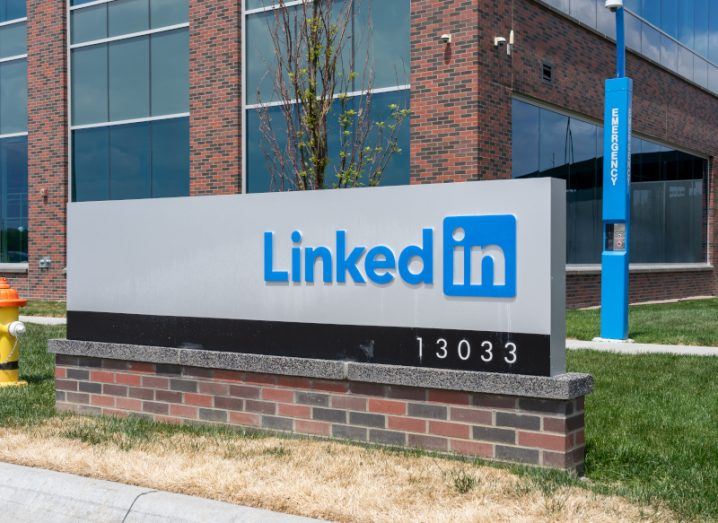 The LinkedIn logo on a white sign in front of a brown building.