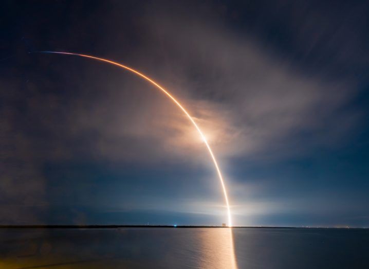 A SpaceX rocket makes an arch of light over the horizon as it is launched into space with Starlink satellites.