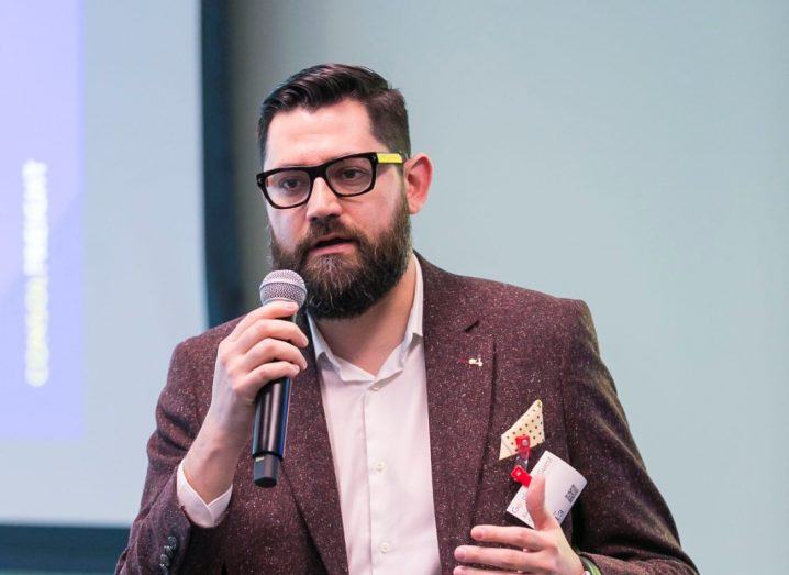 Defactor Labs co-founder Alejandro Gutierrez speaking to an audience using a microphone in his hand.