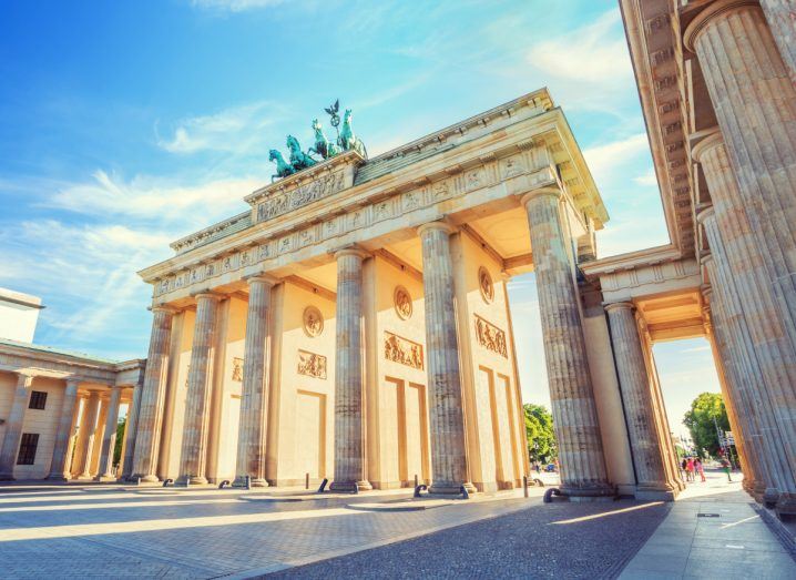 Photo of the Brandenburg Gate in Berlin during the day. Sunlight falls on the pillars of the structure with sculptures on top.