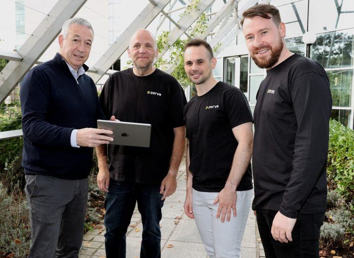 Four men stand next to each other for a photograph. One of them is holding an iPad in his hand while the other three are wearing T-shirts with the Zerve logo on them.