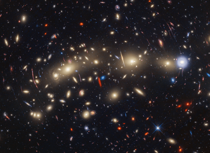An image of multiple galaxies and stars in different colours in distant space.
