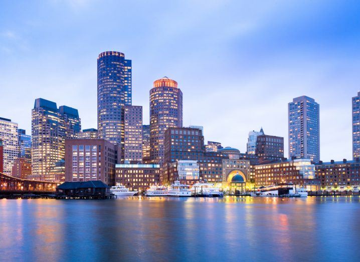 Skyline of the financial district of Boston with large buildings and water in the foreground.