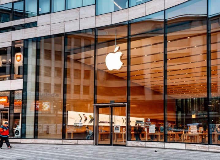 Apple logo on a glass building as seen from the street.