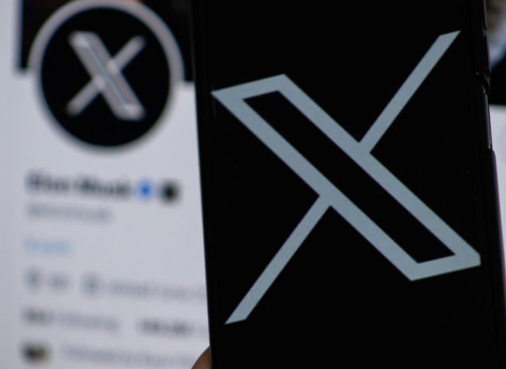 The X logo on a smartphone and on a desktop in the background.