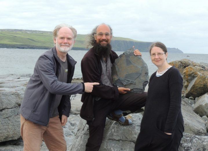 Three scientists with the sponge fossil preserved in rock near the Cliffs of Moher.