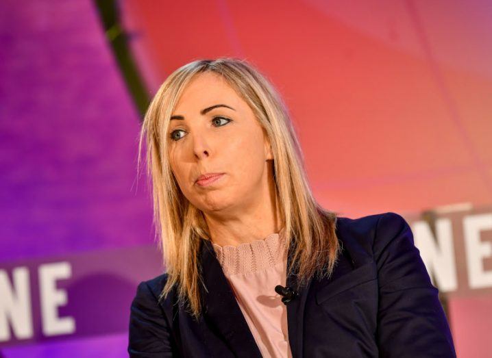 Helen Dixon wearing a black outfit and sitting on a stage.