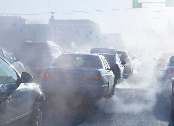 Multiple vehicles in traffic with smoke visible all over the image, to show the concept of air pollution.