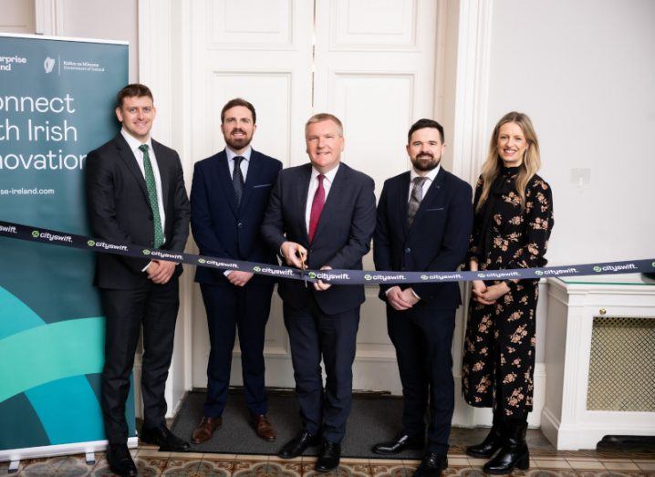 Members of CitySwift, Enterprise Ireland and Minister Michael McGrath standing in front of a ribbon that is about to be cut.