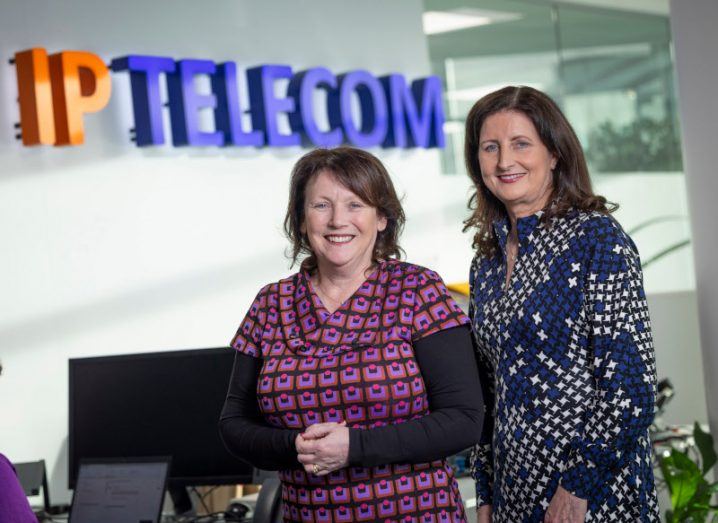 Shena Brien and Edel Creely standing in an office with the IP Telecom logo on a wall behind them.