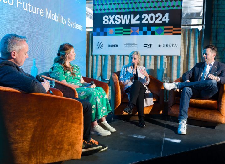 Two women and two men seated on a stage talking. There is a sign behind them that has the SXSW logo on it.