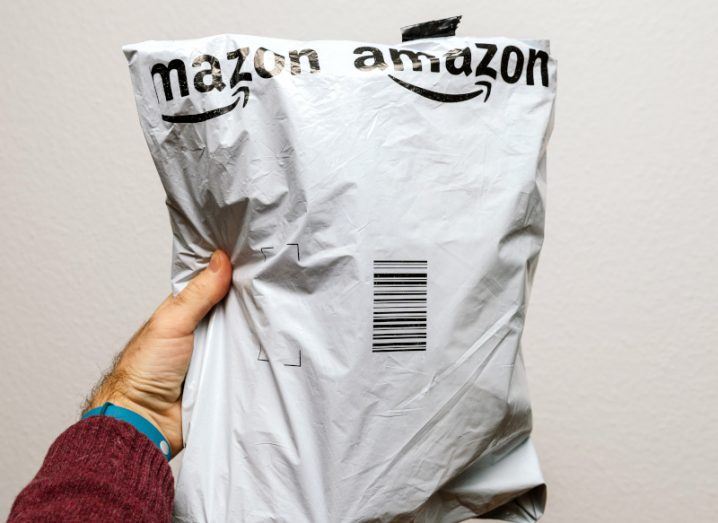 A person's hand holding a plastic Amazon package.