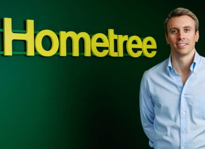 Founder and CEO Simon Phelan standing next to a wall that has the Hometree logo on it.