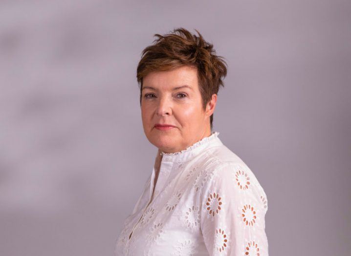 A woman wearing a white blouse smiles at the camera while facing towards the left of the frame. She is Tracy Duffy.