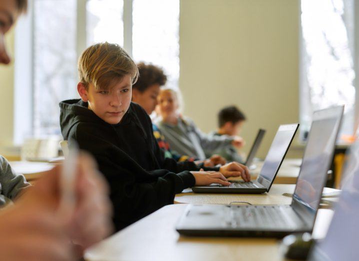 Multiple children looking at laptops while sitting in front of a table.