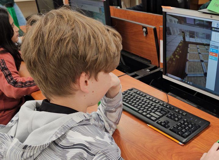 A young boy playing Minecraft Education on a computer screen.