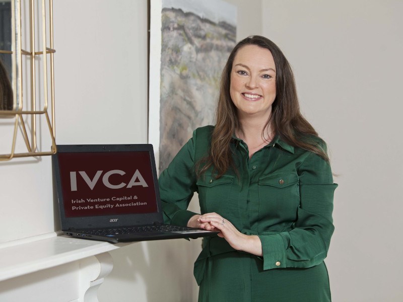 Photo of IVCA director general Sarah-Jane Larkin standing next to a laptop that has IVCA written on the screen.
