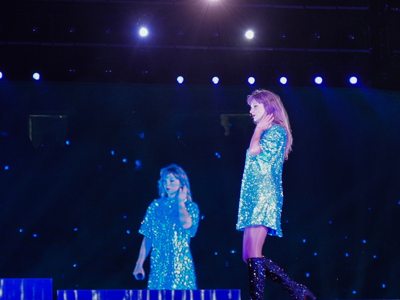 Taylor Swift performing on stage, with an image of her on a screen in the background.