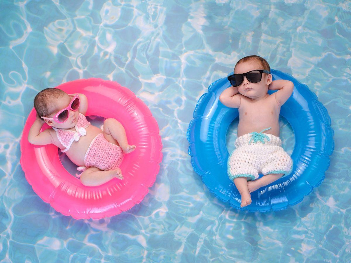 Two babies sleeping in inflatable floats on a swimming pool while wearing sunglasses.