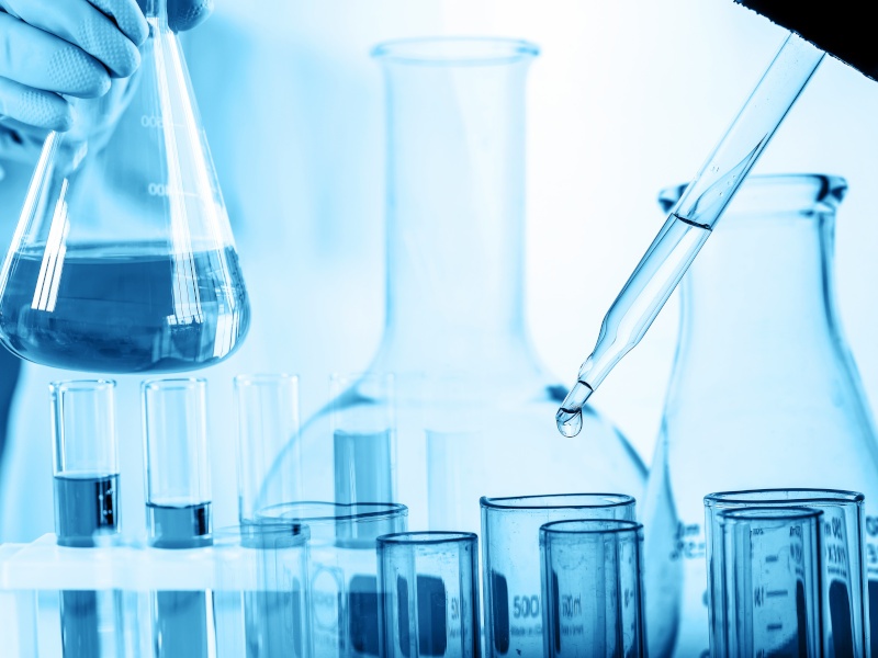 A scientist putting liquid into some test tubes in a lab.