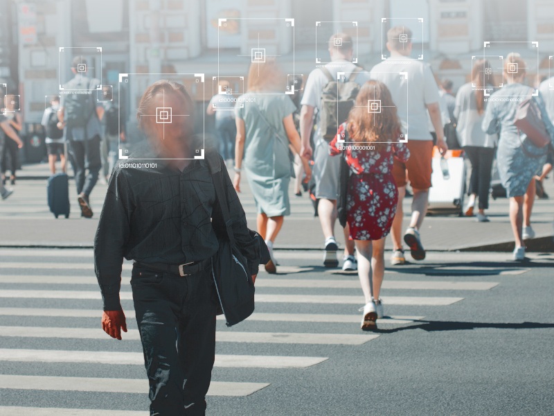 People walking on the street with digital squares covering their heads. Used for the concept of facial recognition technology.