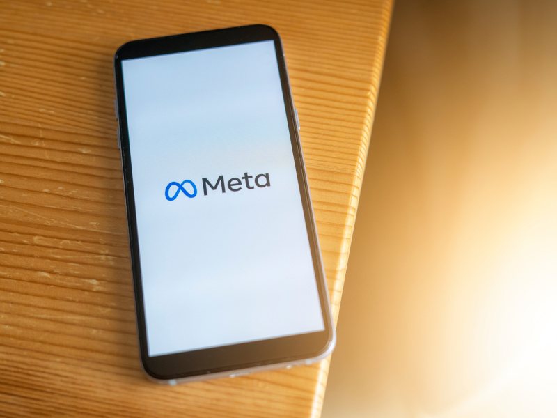 The Meta logo on the screen of a smartphone that is laying on a table.