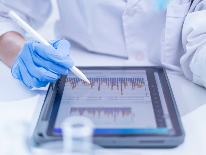 A person wearing blue medical gloves while looking at data on a large tablet.
