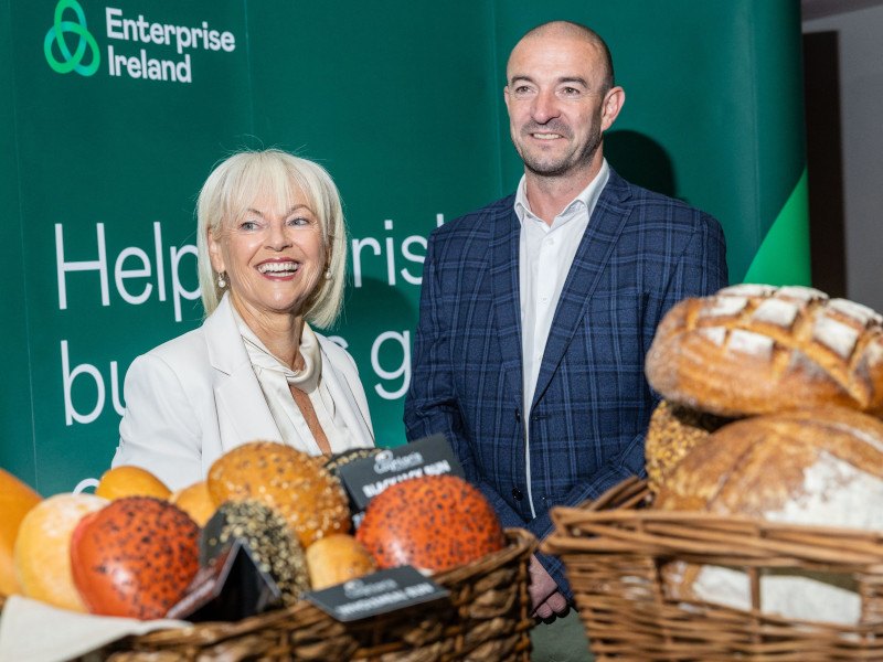 A man and a woman stand behind a table full of food at an Enterprise Ireland Food Innovation Summit.