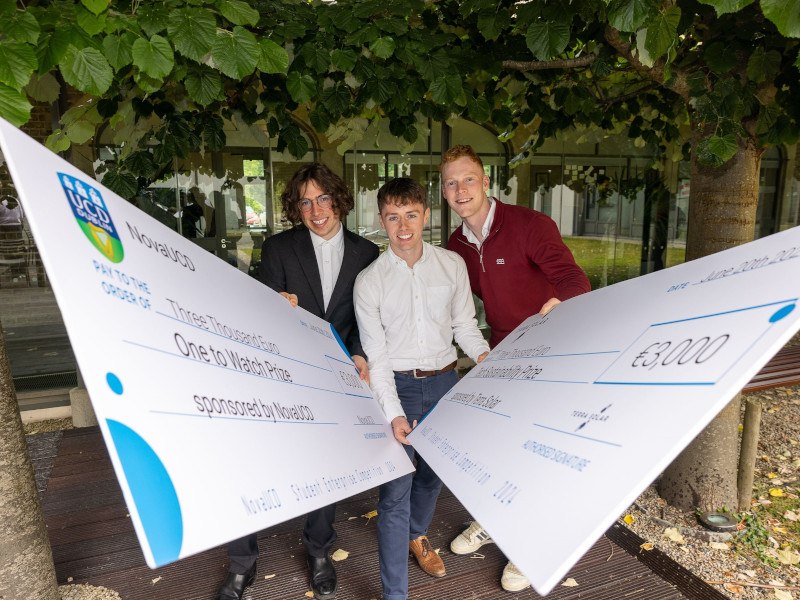 Three students holding two large cheques from NovaUCD after winning the accelerator programme.