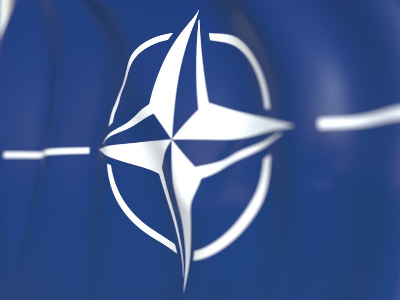 Close-up of the NATO logo on a flag.