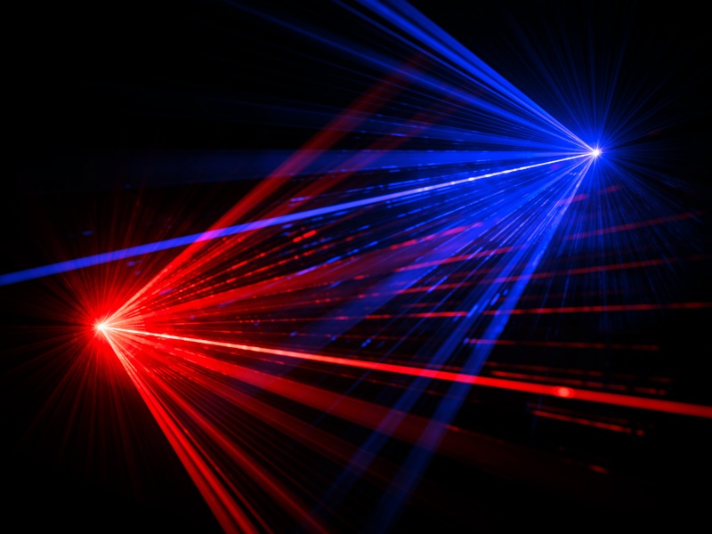 A red and a blue light shining in a dark background, with beams stemming out from both light sources. Used for the concept of laser sensors.