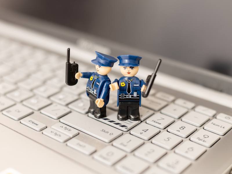 Two toy police officers on a keyboard. Used for the concept of law enforcement dealing with illegal software.