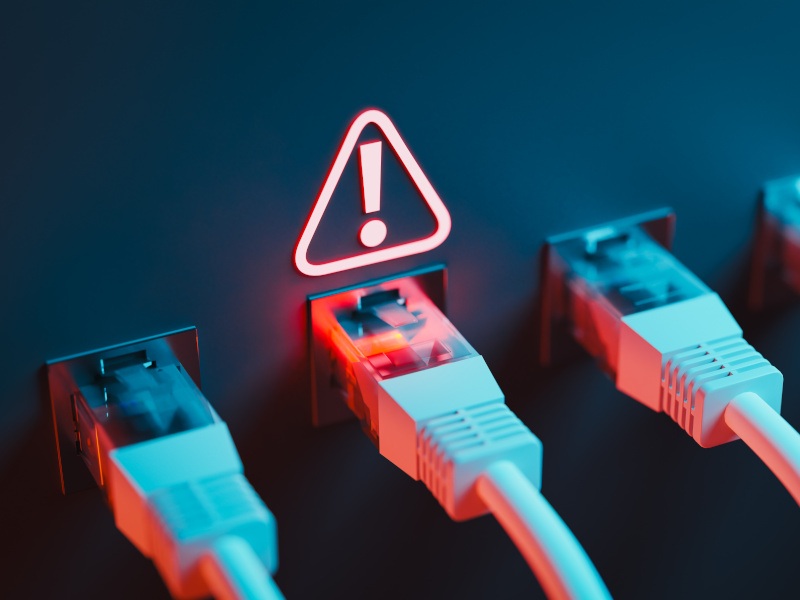 A bunch of cables in sockets with a red warning symbol above one. Used for the context of a Microsoft outage.