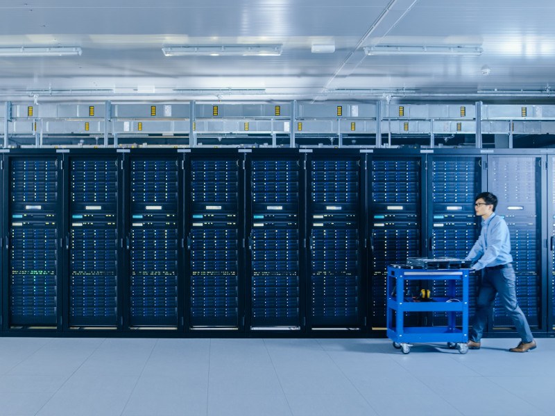 Man inside a data centre walking past a row of servers.