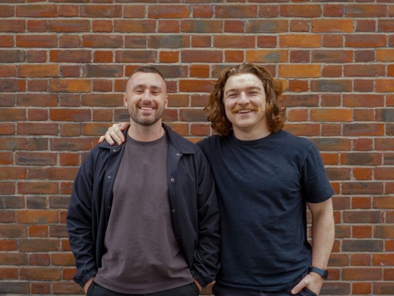 Headshot of the two founders of Solidroad in standing in front of a brick wall.