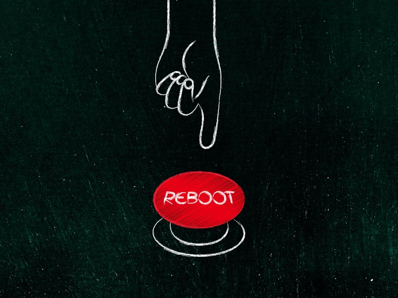 An image of a red button with 'reboot' written on it and a drawing of a hand reaching down to press it with a finger.