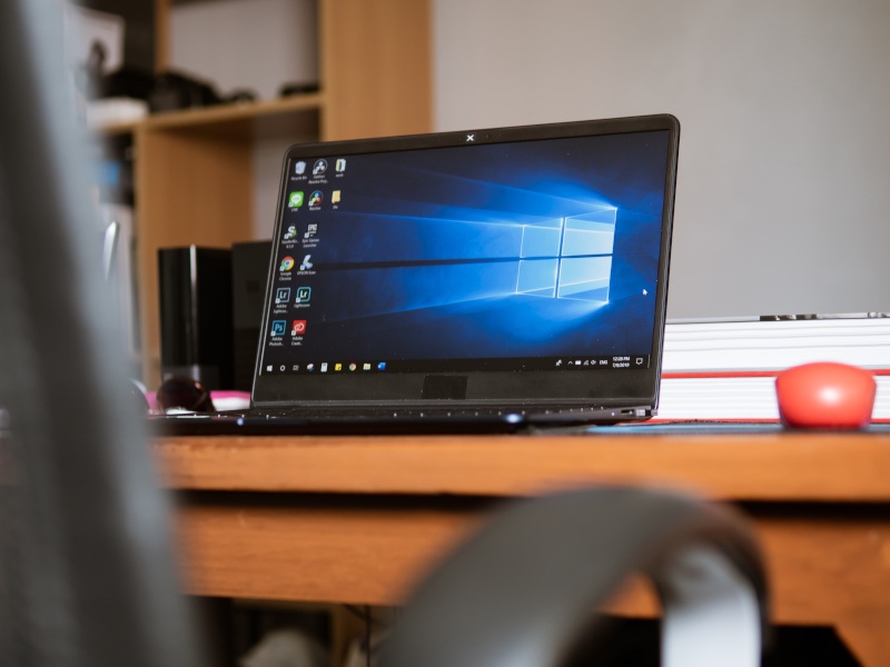 A laptop on a table with the Windows logo on the screen. Used for the context of the Windows Control Panel being replaced.